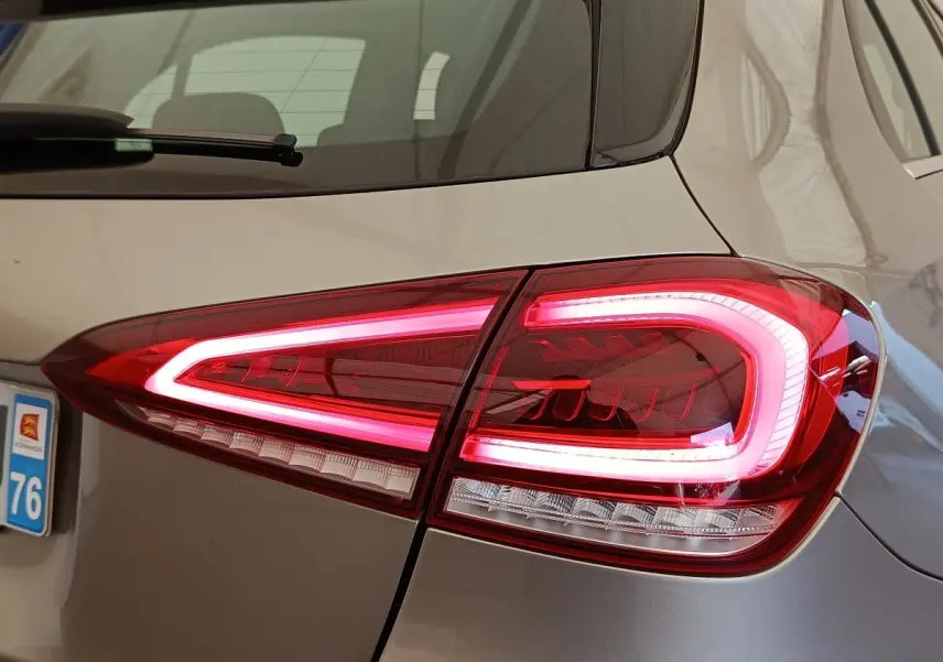 Gros plan sur le feu arrière droit allumé d’une Mercedes Classe A gris clair, avec partie de la lunette arrière visible.