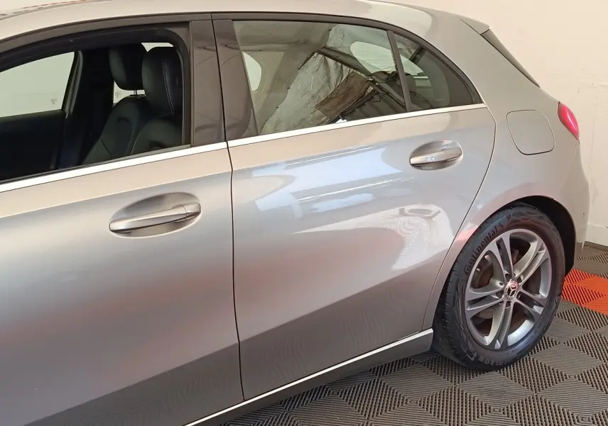 Vue latérale droite d'une Mercedes Classe A A 180 Business Line gris clair, avec jantes alliage et poignées de porte intégrées.
