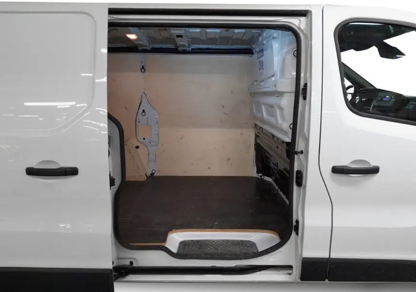 Vue latérale gauche du Renault Trafic Fourgon blanc minéral 2024 avec porte coulissante ouverte sur l’espace de chargement vide.