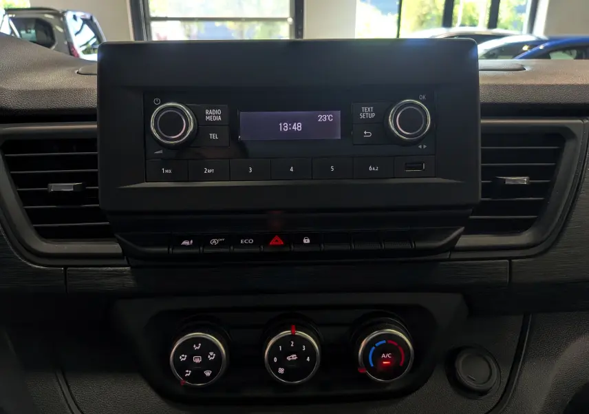 Vue rapprochée du tableau de bord du Renault Trafic Fourgon 2024, avec commandes radio et climatisation visibles.