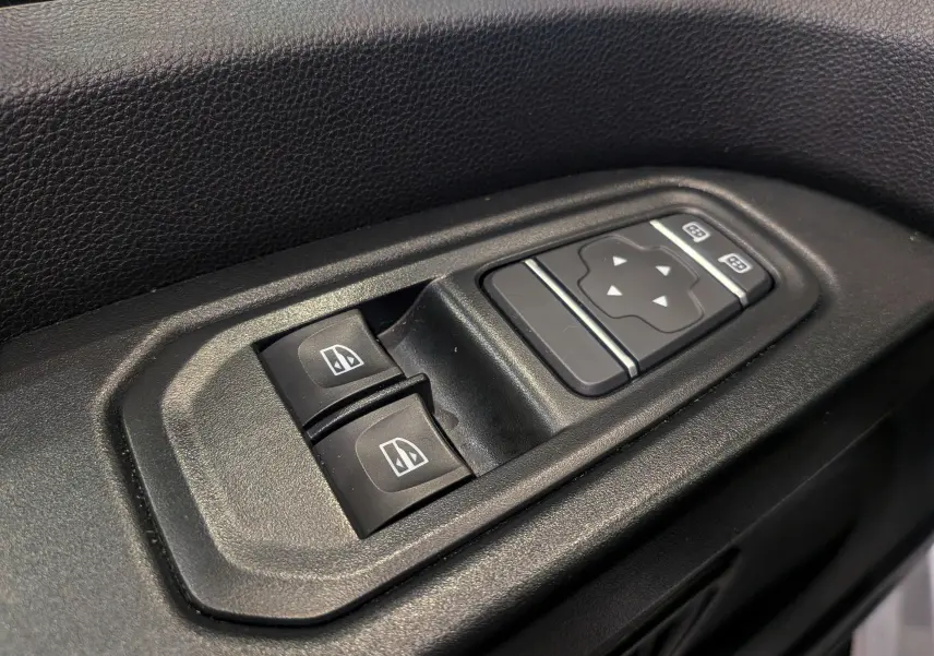 Gros plan sur les commandes de lève-vitres et réglage des rétroviseurs côté conducteur du Renault Trafic Fourgon blanc 2024.