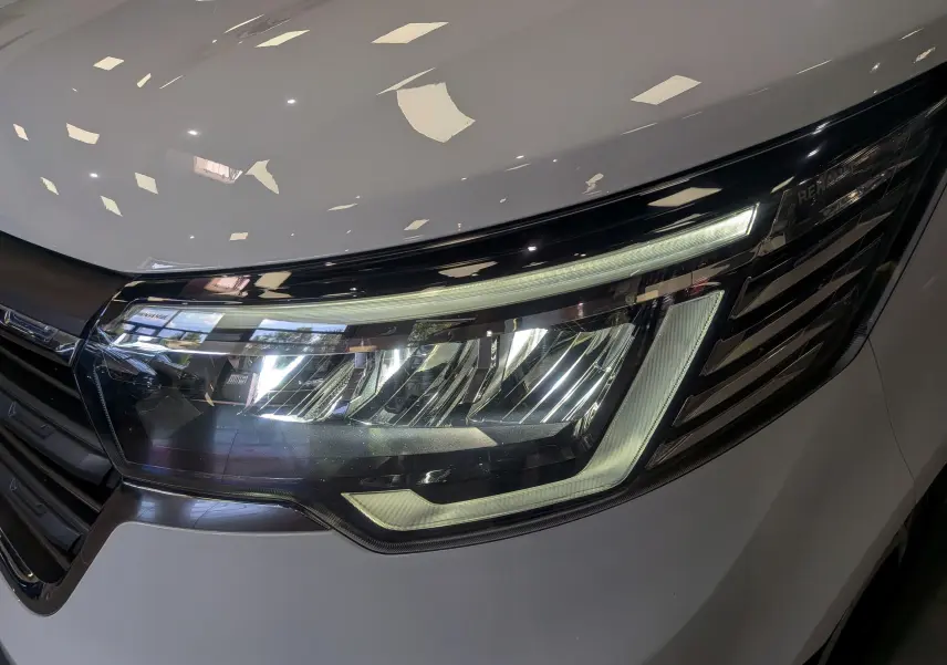 Gros plan sur le phare avant droit du Renault Trafic Fourgon blanc minéral 2024 avec éclairage LED distinctif.