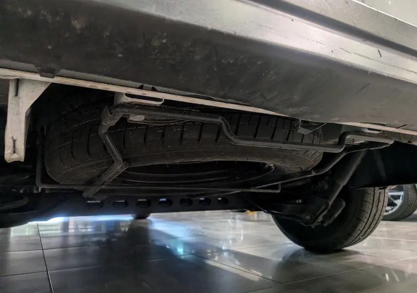 Vue en contre-plongée sous le Renault Trafic Fourgon blanc montrant la roue de secours suspendue sous le châssis.