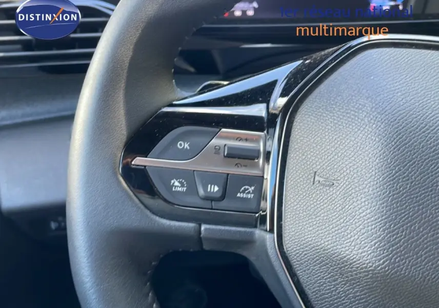 Gros plan sur le volant multifonction noir de la Peugeot 308 SW Hybrid 2025 avec commandes intégrées côté gauche.