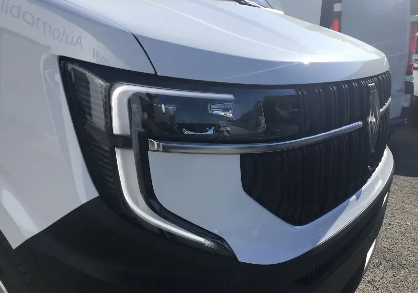 Gros plan sur l'avant gauche du Renault Master blanc 2025, mettant en valeur son phare moderne et sa calandre noire distinctive.