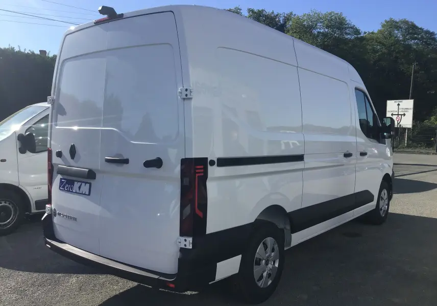 Vue 3/4 arrière droite d'un Renault Master blanc 2025 avec marquage Zero KM et feux arrière modernes.