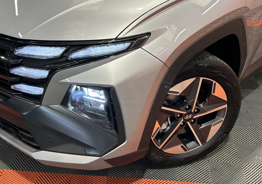 Gros plan sur l'avant droit du Hyundai Tucson 2025 Shimmering Silver, avec phares LED et jante 18 pouces design.