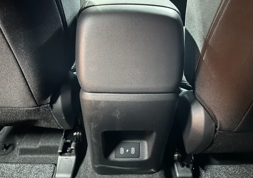 Prise USB arrière entre les sièges noirs du Hyundai Tucson 2025 STYLE hybride en intérieur sombre.