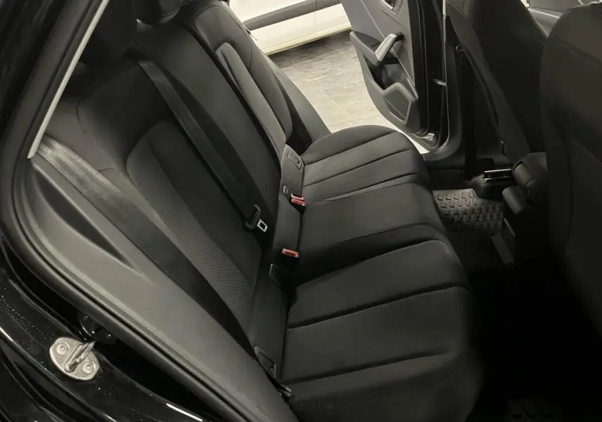 Vue intérieure arrière côté gauche de l'Audi Q2 2022 noire, montrant la banquette arrière en tissu noir et la portière ouverte.