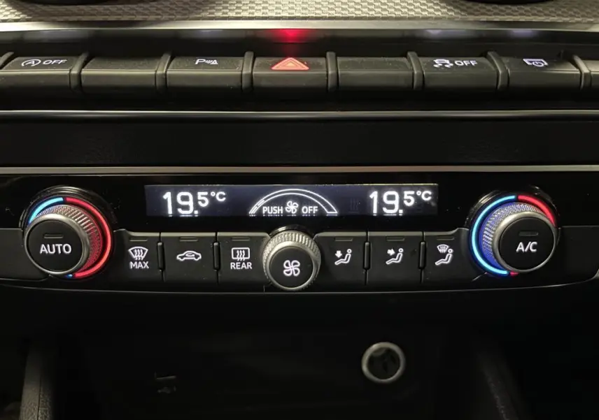 Panneau de climatisation automatique avec réglages à 19,5°C et boutons lumineux dans l'Audi Q2 Business line noir.