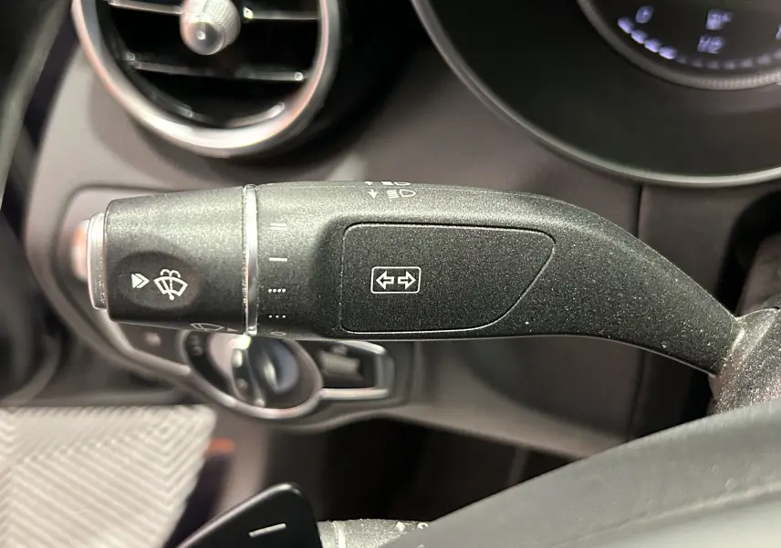 Gros plan sur la commande de clignotant et essuie-glace dans l'habitacle d'une Mercedes Classe C 200d bleue de 2018.