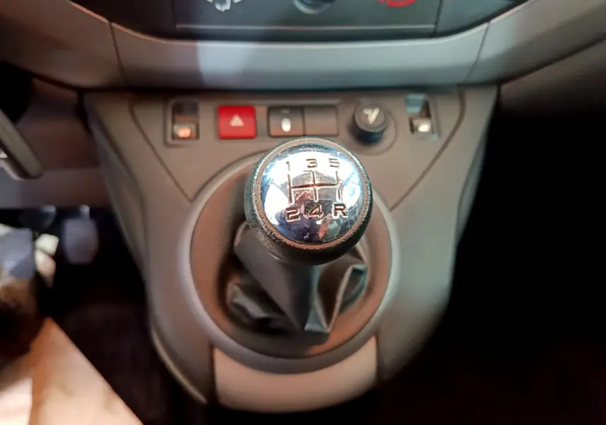 Gros plan sur le levier de vitesses manuel du Citroën Berlingo BlueHDi 75 BVM Feel, tableau de bord gris en arrière-plan.