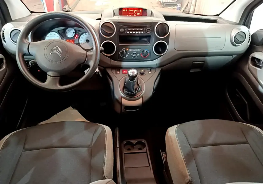 Vue intérieure avant du Citroën Berlingo 2016, tableau de bord gris avec volant et levier de vitesse manuel visibles.