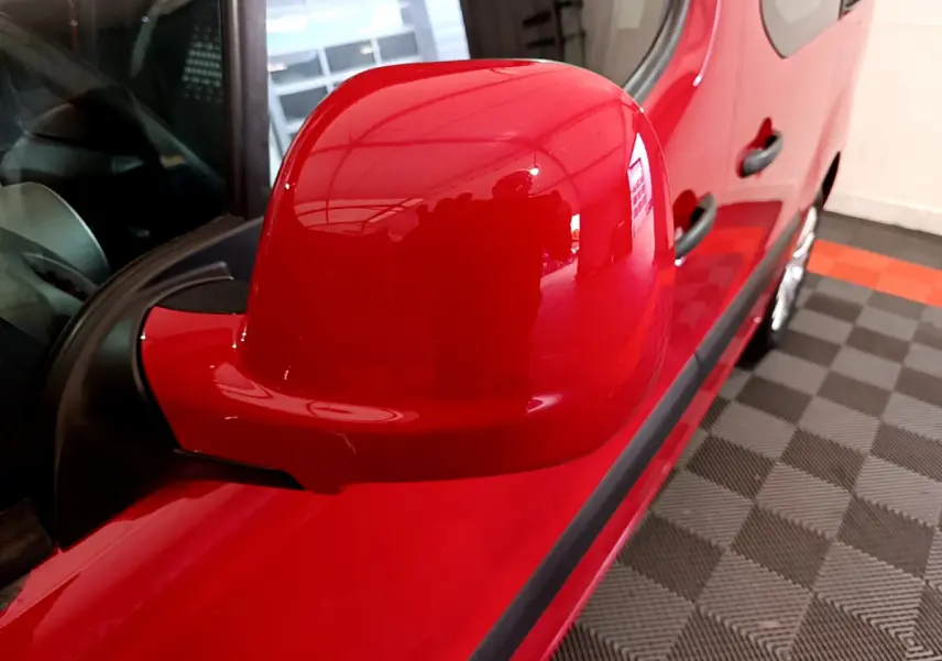 Rétroviseur côté gauche rouge brillant du Citroën Berlingo 2016, avec reflet de l'intérieur et partie de la porte visible.