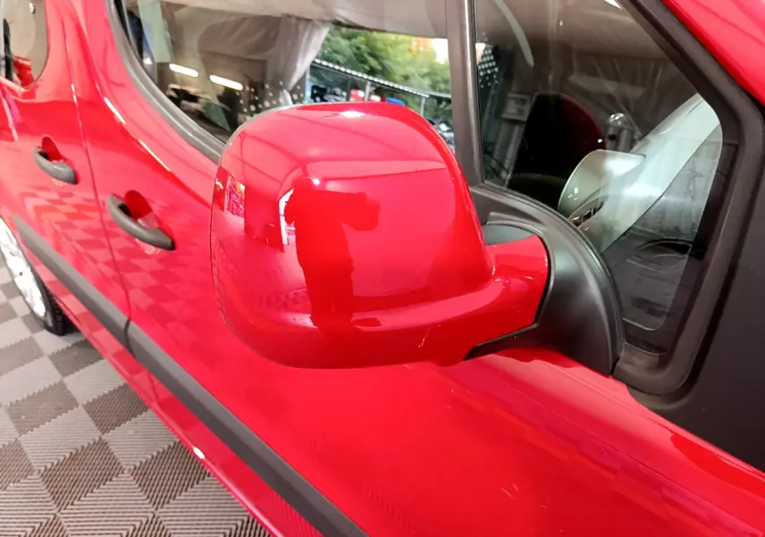 Gros plan sur le rétroviseur côté conducteur rouge d'un Citroën Berlingo 2016, avec portières et poignées visibles.