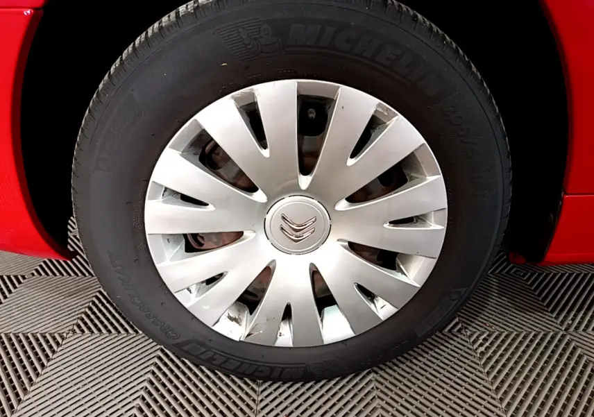 Gros plan sur la roue avant gauche rouge d’un Citroën Berlingo 2016 avec enjoliveur argenté et pneu Michelin.