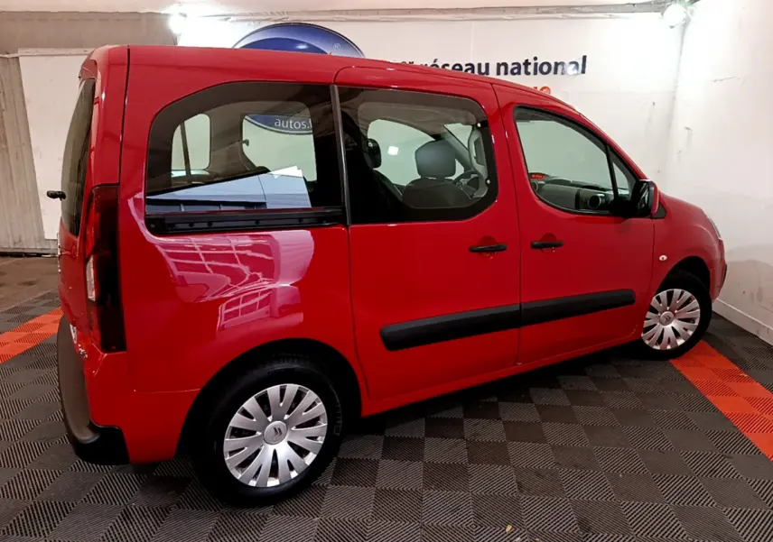 Vue 3/4 arrière côté gauche d'un Citroën Berlingo rouge 2016 avec vitres teintées et jantes acier à enjoliveurs.