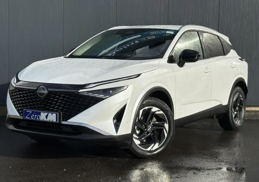 Nissan Qashqai blanc nacré en 3/4 avant droit, avec calandre noire texturée et jantes alliage noires.