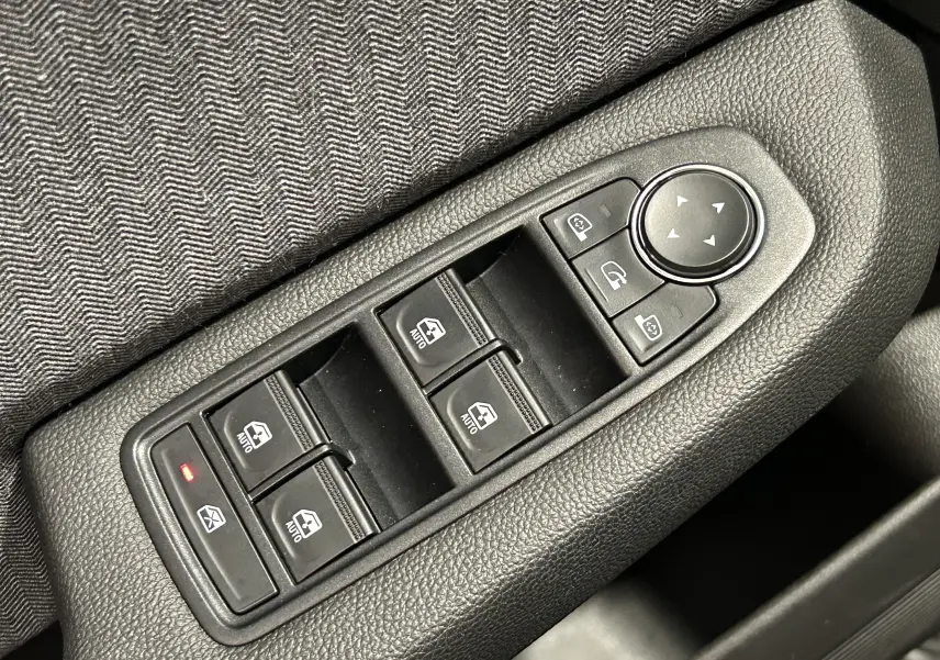Gros plan sur les commandes de lève-vitres et réglage des rétroviseurs côté conducteur d’une Renault Clio V.