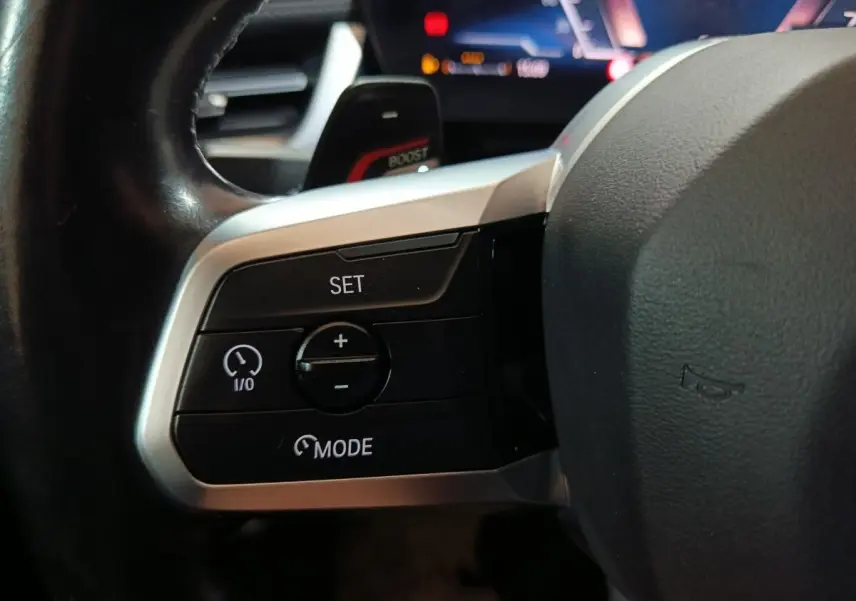 Gros plan sur les commandes de régulateur de vitesse au volant cuir noir du BMW X1 xDrive23i M Sport 2023.