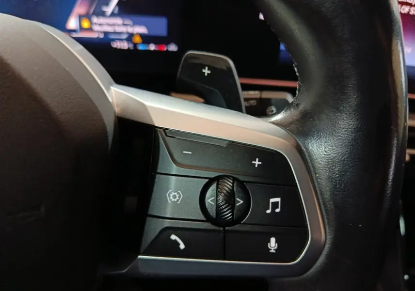 Gros plan sur les commandes multifonctions en cuir noir du volant du BMW X1 xDrive23i M Sport 2023.