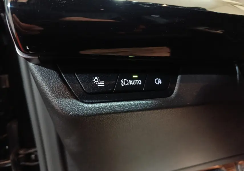 Gros plan sur les commandes d’éclairage automatiques dans l’habitacle noir du BMW X1 xDrive23i M Sport 2023.