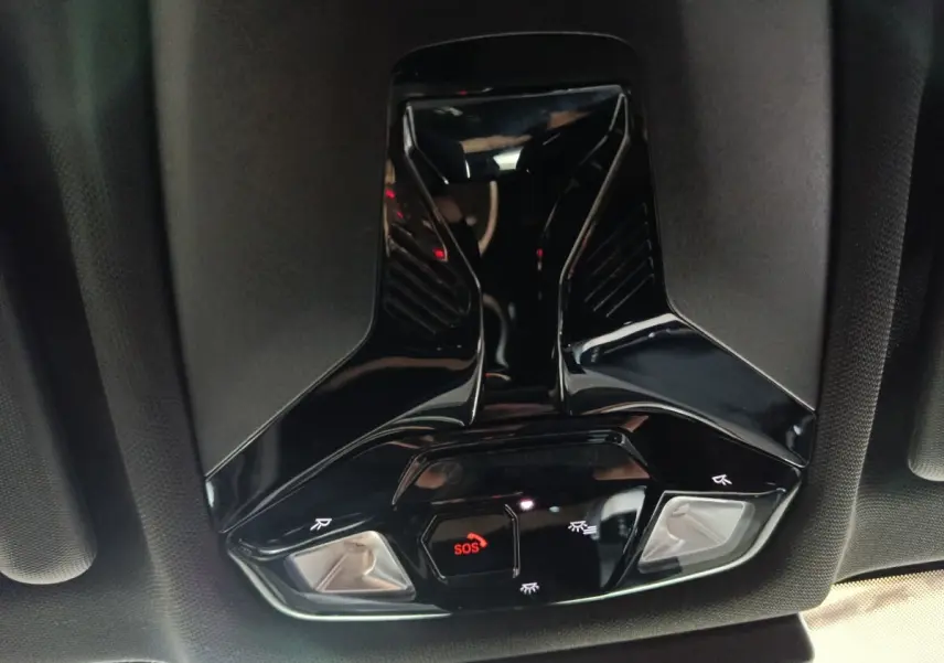 Vue en contre-plongée du plafonnier noir brillant avec bouton SOS rouge et éclairages intégrés dans un BMW X1 2023.