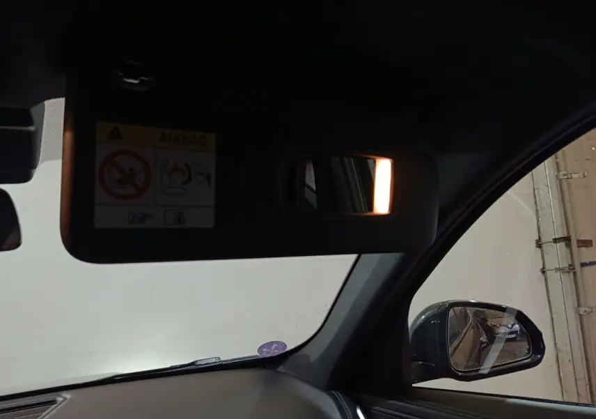 Intérieur BMW X1 noir 2023, vue côté droit sur pare-soleil avec miroir éclairé et rétroviseur extérieur.