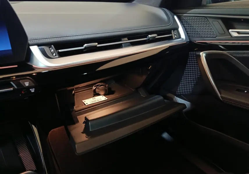 Vue intérieure côté passager du tableau de bord noir et boîte à gants ouverte du BMW X1 xDrive23i M Sport 2023.