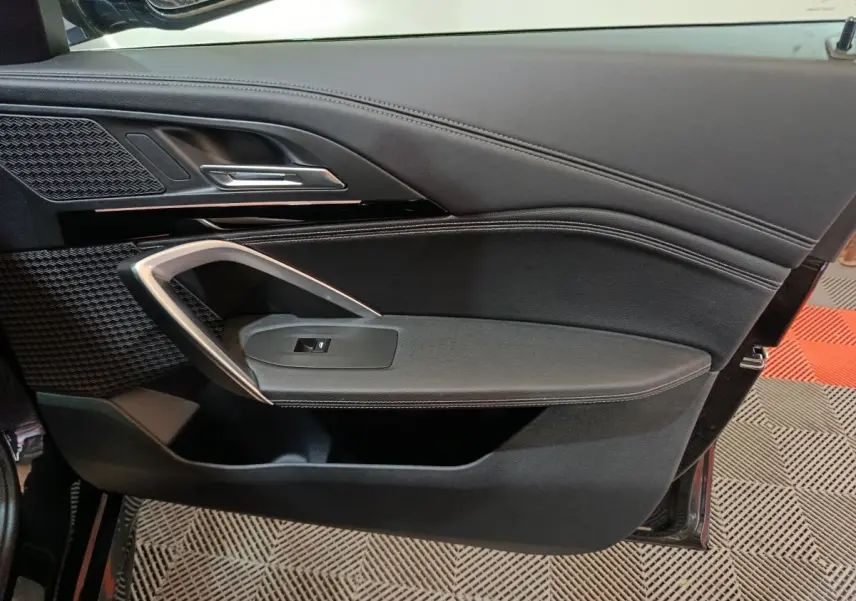 Vue rapprochée de la porte intérieure côté gauche noire du BMW X1 xDrive23i M Sport 2023 avec détails chromés et tissu texturé.