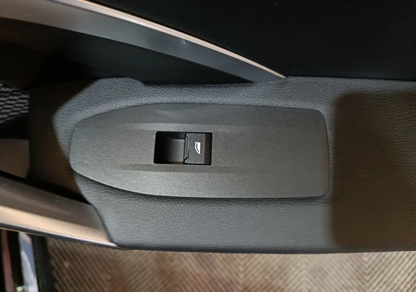 Gros plan sur le bouton de commande de la vitre électrique, sur la porte intérieure noire d’une BMW X1 2023.