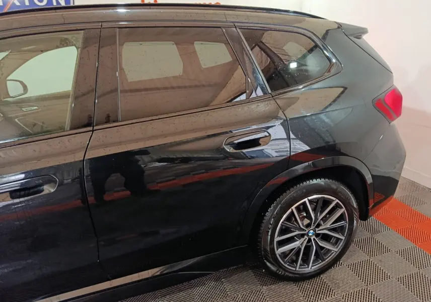 Vue latérale droite d'un BMW X1 xDrive23i M Sport noir, mettant en valeur les jantes alliage et les vitres teintées.