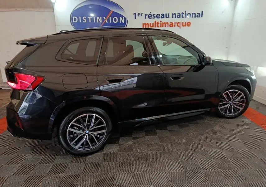 BMW X1 xDrive23i M Sport noir vue de profil côté gauche, avec jantes alliage et feux arrière LED allumés.