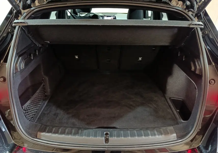 Coffre ouvert vu de l'arrière d'un BMW X1 noir 2023, montrant l'espace de chargement et la tablette de séparation.