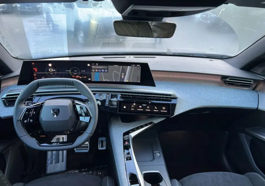 Vue intérieure avant du Peugeot 3008 Hybrid 145 GT Alcantara, tableau de bord gris avec écran numérique panoramique et volant cuir multifonctions.