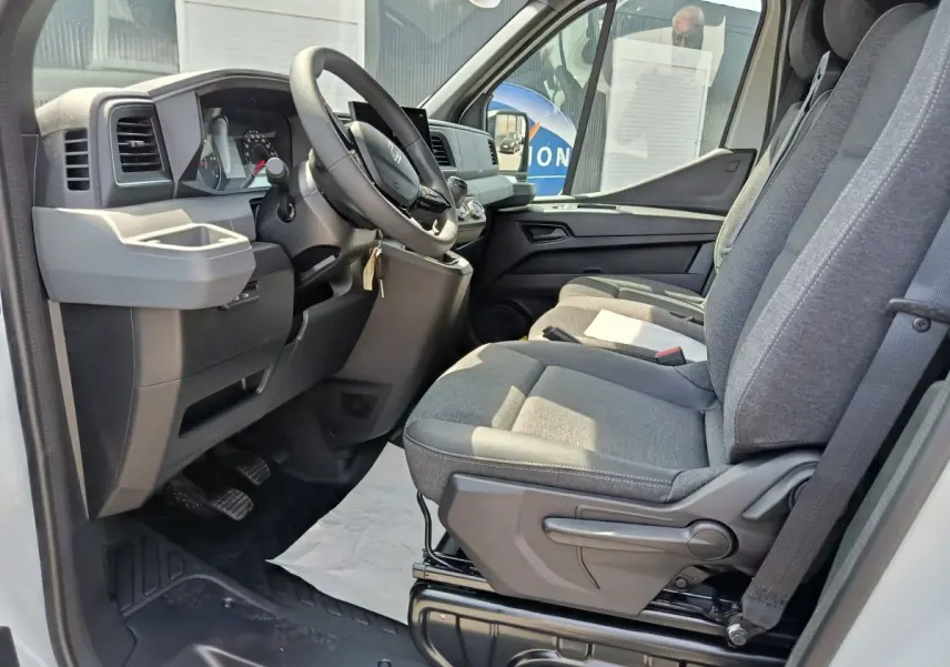 Intérieur côté conducteur du Renault Master blanc 2025, montrant le tableau de bord et les sièges gris en tissu.