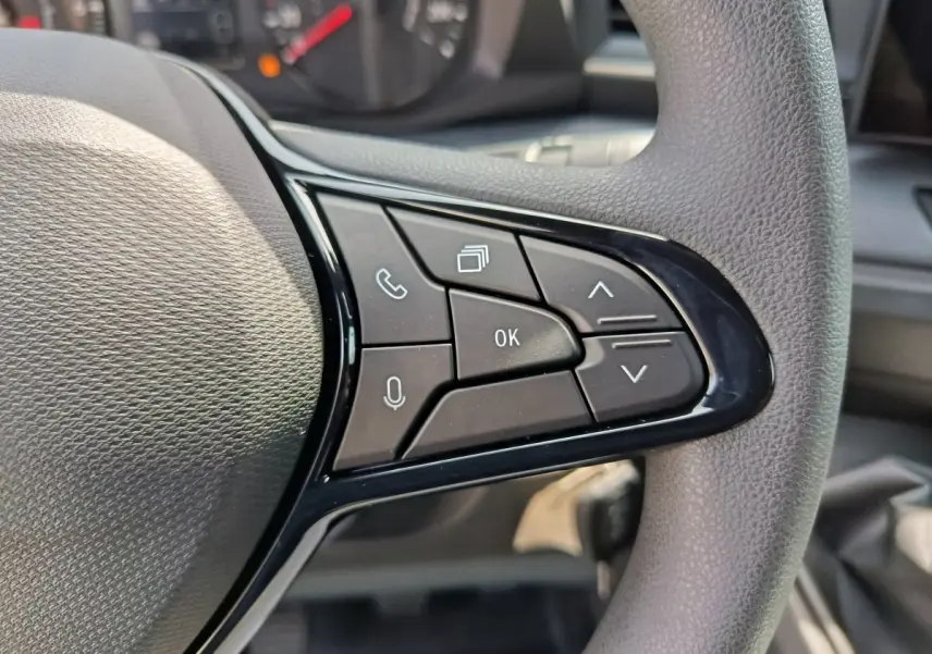 Gros plan sur les commandes multifonctions noires du volant du Renault Master blanc, avec tableau de bord en arrière-plan.