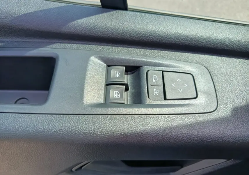 Gros plan sur les commandes de réglage des vitres et des rétroviseurs côté gauche du Renault Master blanc.