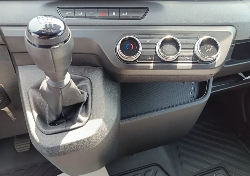 Gros plan intérieur sur la console centrale du Renault Master blanc 2025, avec levier de vitesses manuel et commandes climatisation.