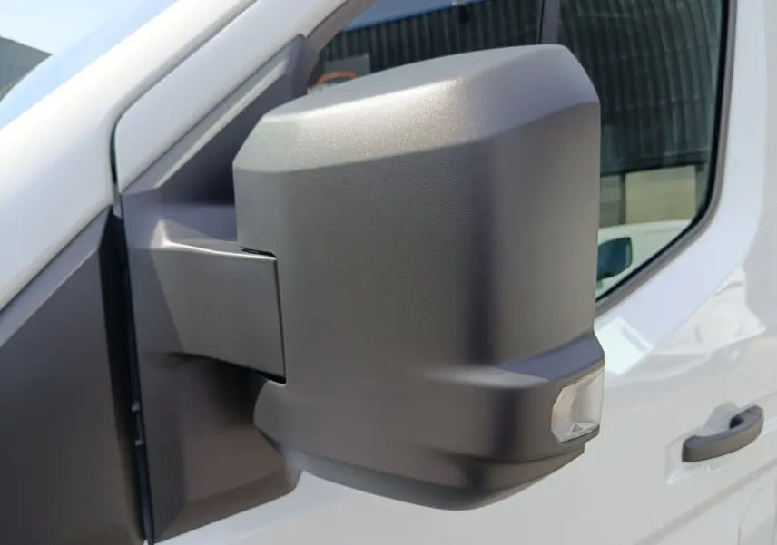 Gros plan sur le rétroviseur droit noir mat du Renault Master blanc, avec porte et vitre partiellement visibles.