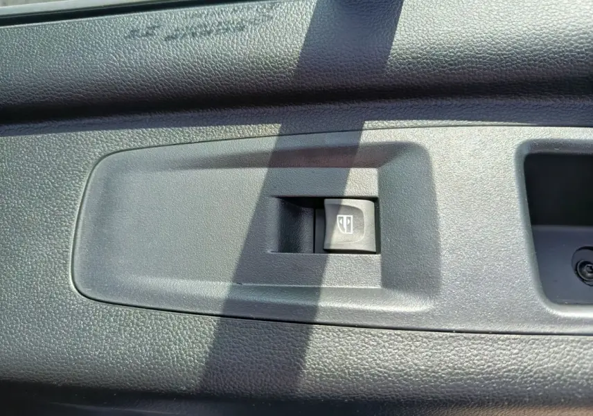 Bouton de commande de lève-vitre électrique sur la porte intérieure noire du Renault Master FG L2H2 blanc, vue rapprochée.
