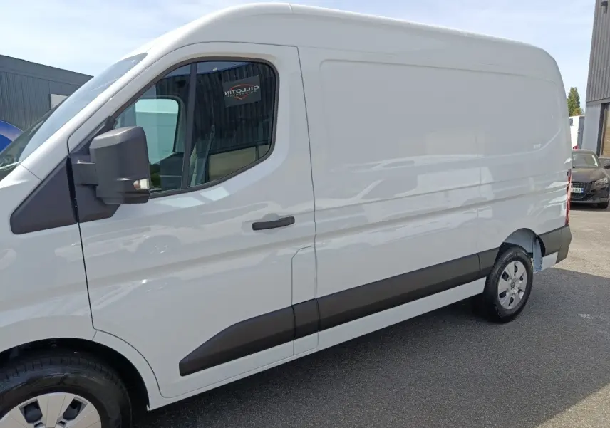 Vue latérale droite d’un utilitaire blanc Renault Master FG L2H2 avec protections noires sur les portières et rétroviseur noir.