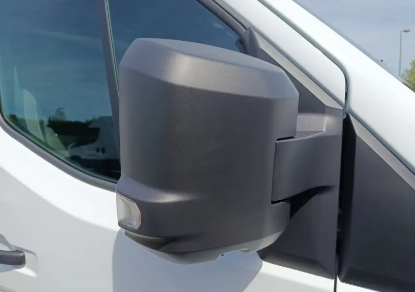 Gros plan sur le rétroviseur droit noir d’un Renault Master blanc, avec fenêtre avant et reflet visible.