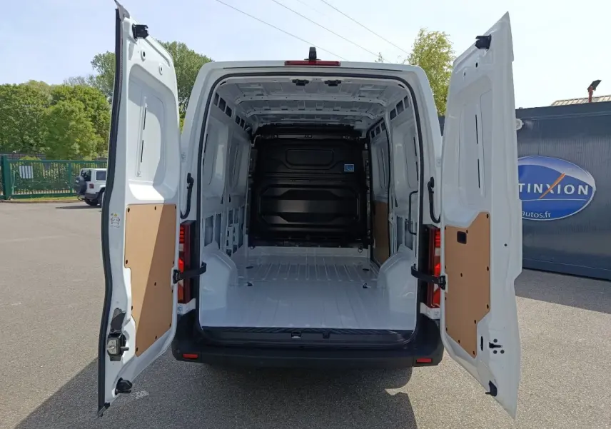 Vue arrière du Renault Master blanc 2025 avec portes arrière ouvertes montrant l'espace de chargement vide et cloison pleine noire.