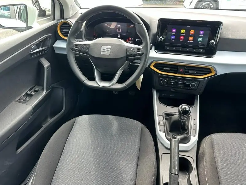 Intérieur SEAT Arona 2025 vu de face, volant cuir multifonction, écran tactile, détails jaunes autour des aérateurs.