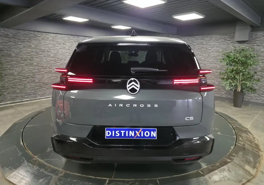 Vue arrière d'un Citroën C5 Aircross gris métallisé avec feux arrière LED horizontaux et logo central lumineux.
