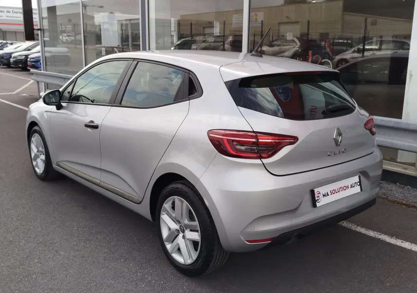 Vue 3/4 arrière droite d'une Renault Clio V Business gris platine, avec feux arrière LED et jantes alliage visibles.