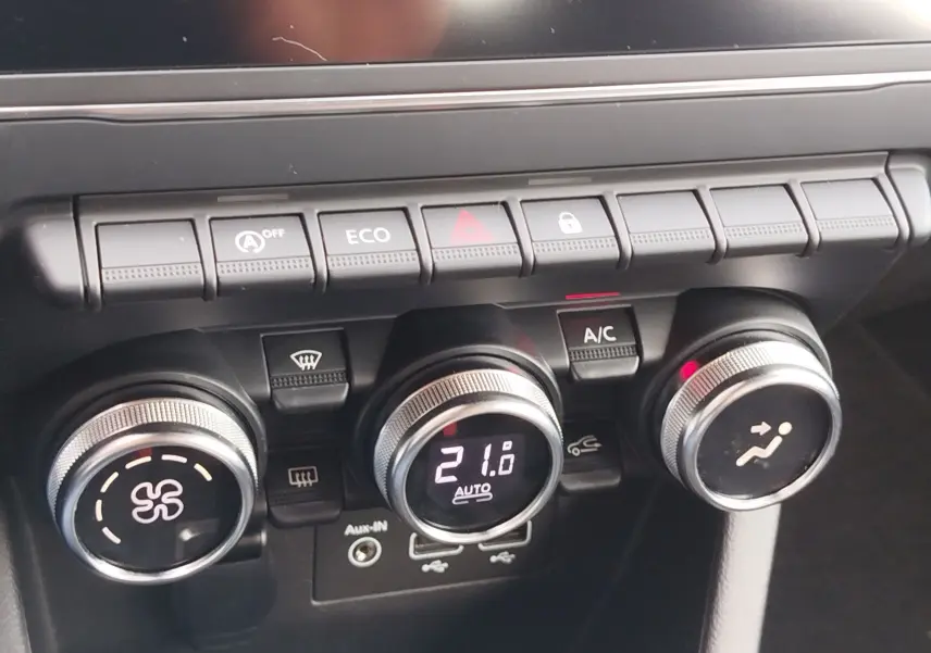 Gros plan sur la console centrale de la Renault Clio V Business, montrant les commandes de climatisation et les boutons fonctionnels.