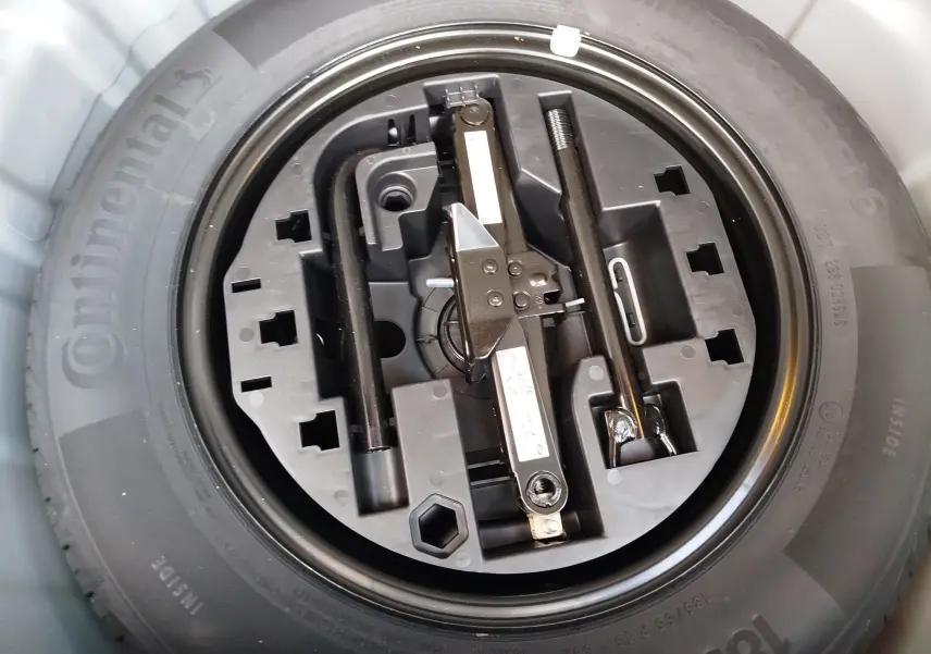 Gros plan sur la roue de secours et le kit d’outils intégré d’une Renault Clio V Business gris platine, vue de dessus.