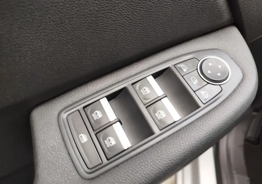 Gros plan sur les commandes de lève-vitres et réglage des rétroviseurs côté conducteur de la Renault Clio V Business gris platine.
